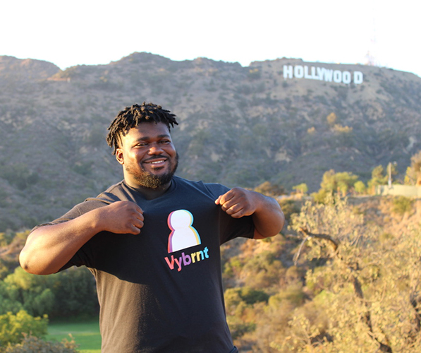 Founder Joel Sakyi in front of Hollywood sign with Vybrnt t-shirt