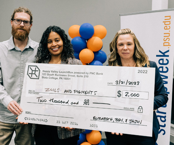 Zoils & Pigments founders stand with Happy Valley LaunchBox powered by PNC Bank Director holding a check awarded to Zoils & Pigments