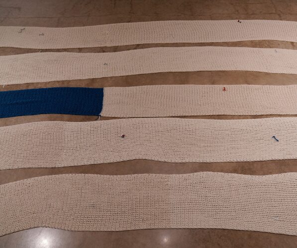 long, large knitted materials laid out in horizontal rows