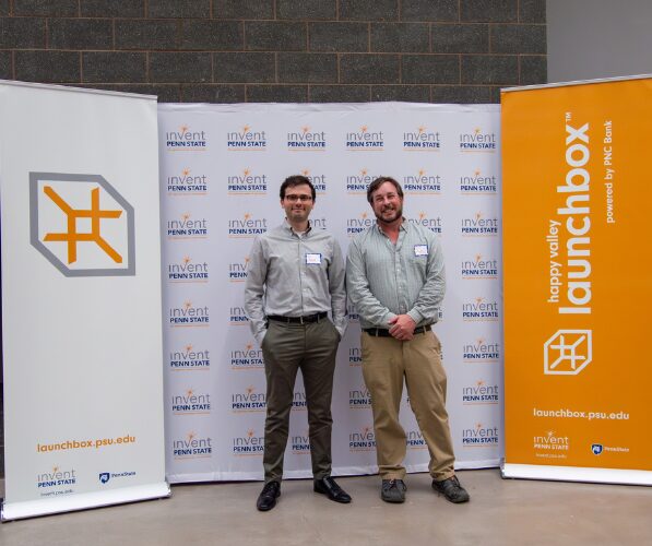 Ali and Sven pose for a photo in front of Invent Penn State signage