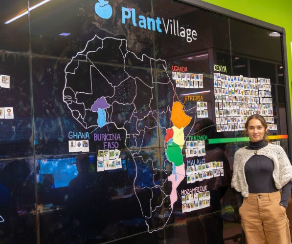 Annalyse stands in front of a map of Africa that notes the different countries where PlantVillage is active