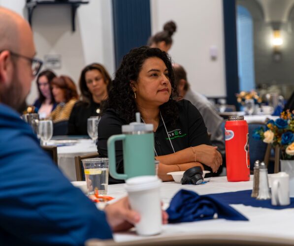 Individual sits at a table wearing an SBDC jacket
